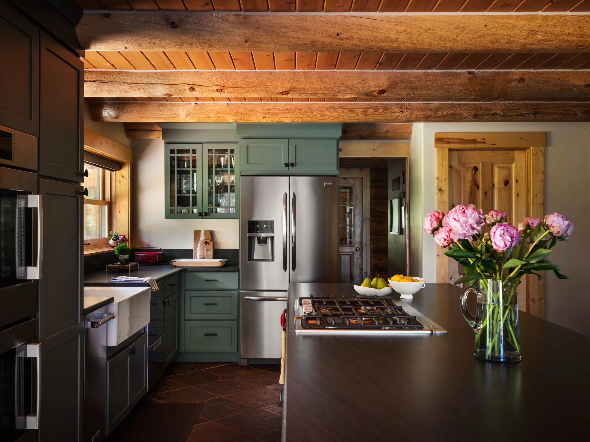 Kitchen with sage green cabinetry, stainless appliances, and fresh peonies — interior design photography Livingston Montana, Sam Schlauch Designs